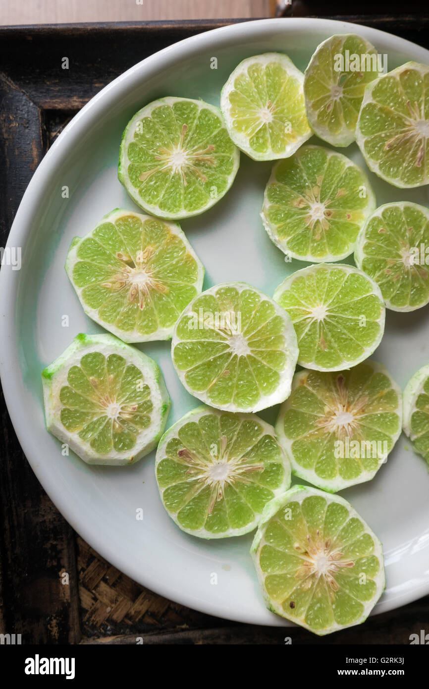 Tranche de citron vert frais pelé sur plaque blanche. Banque D'Images