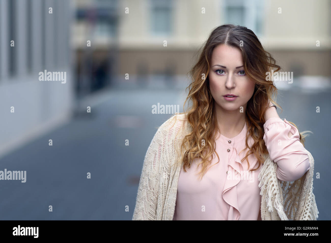 Belle jeune femme seule en blouse rose avec plus de pull blanc qu'il pose en face d'origine urbaine with copy space Banque D'Images