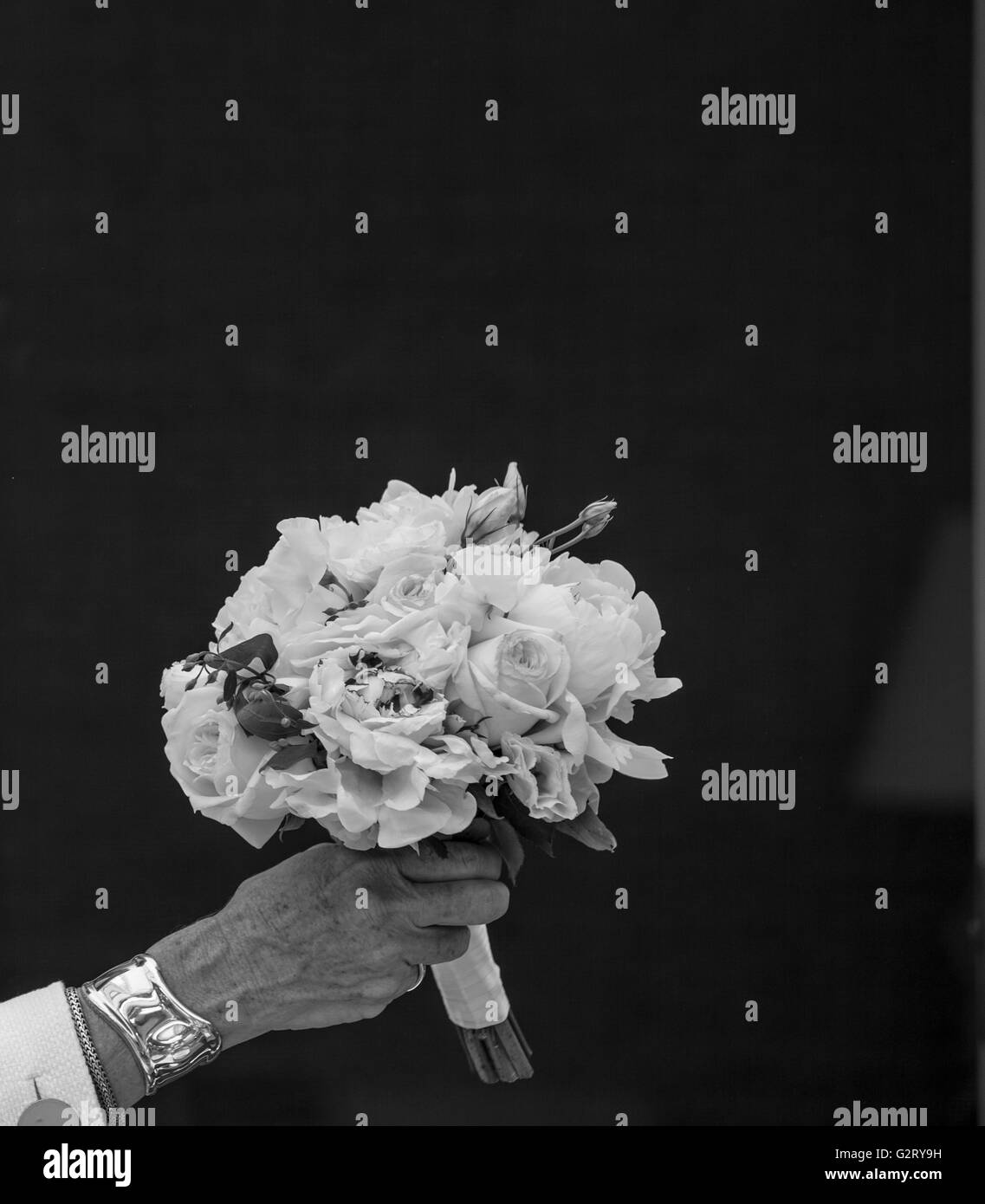 Bouquet de fleurs fraîches coupées en noir et blanc qui s'est tenue à une main de femme avec un fond noir Banque D'Images