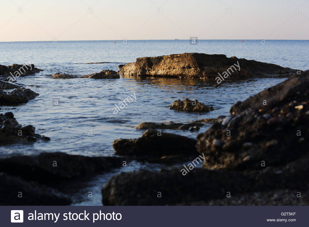 L'aube à travers les roches dans une baie sur l'île de Rhodes en Grèce Banque D'Images