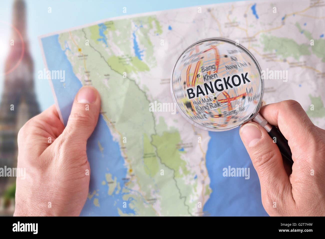 Mains de ramasser une carte de Bangkok et à un emplacement avec une loupe avec monument représentant Banque D'Images