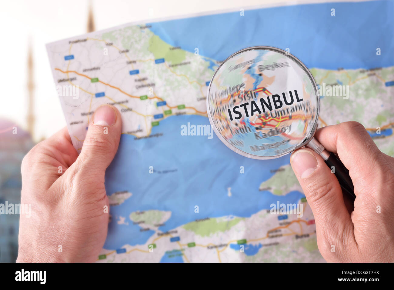 Mains ramasser une carte d'Istanbul et à la recherche d'un endroit à l'aide d'une loupe avec monument représentant Banque D'Images