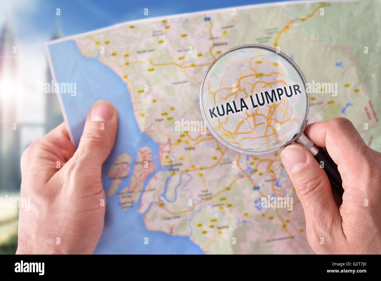 Mains de prendre un plan de Kuala Lumpur et à la recherche d'un endroit à l'aide d'une loupe avec monument représentant Banque D'Images