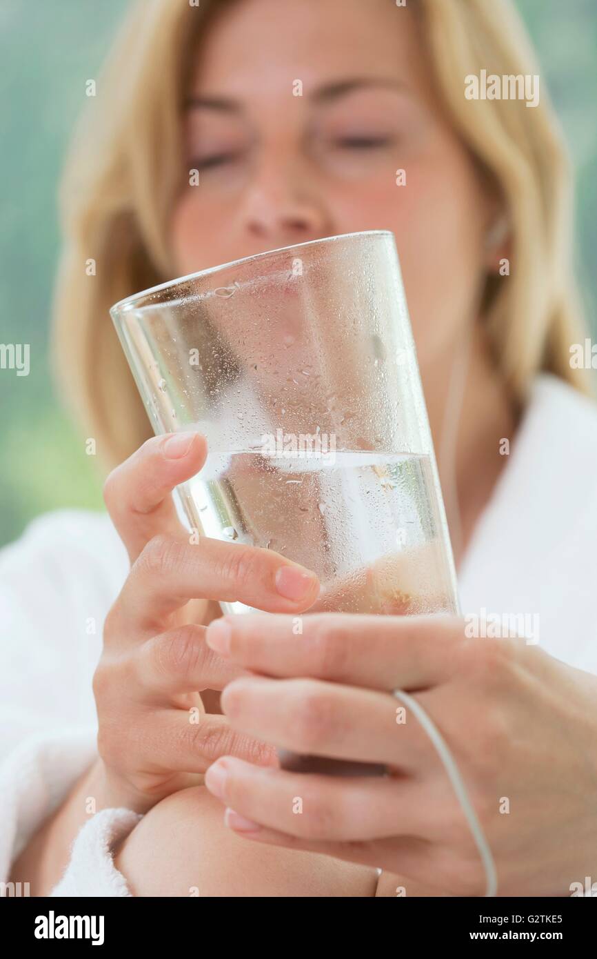 Femme en peignoir blanc tenant un verre d'eau Banque D'Images