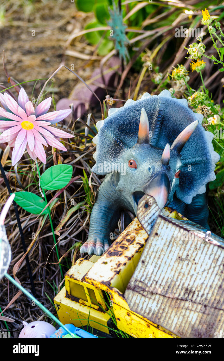 Une cour avec un jouet camion Tonka attaquant un triceratops Banque D'Images