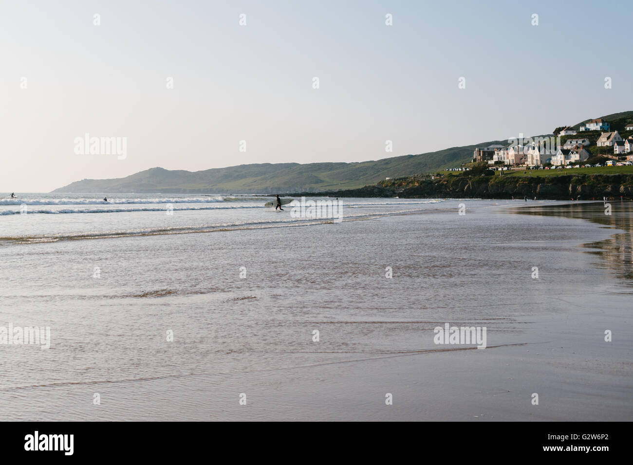 Un internaute entre dans l'eau pour rejoindre d'autres surfers équitation les vagues à la plage de Woolacombe, Devon UK Banque D'Images