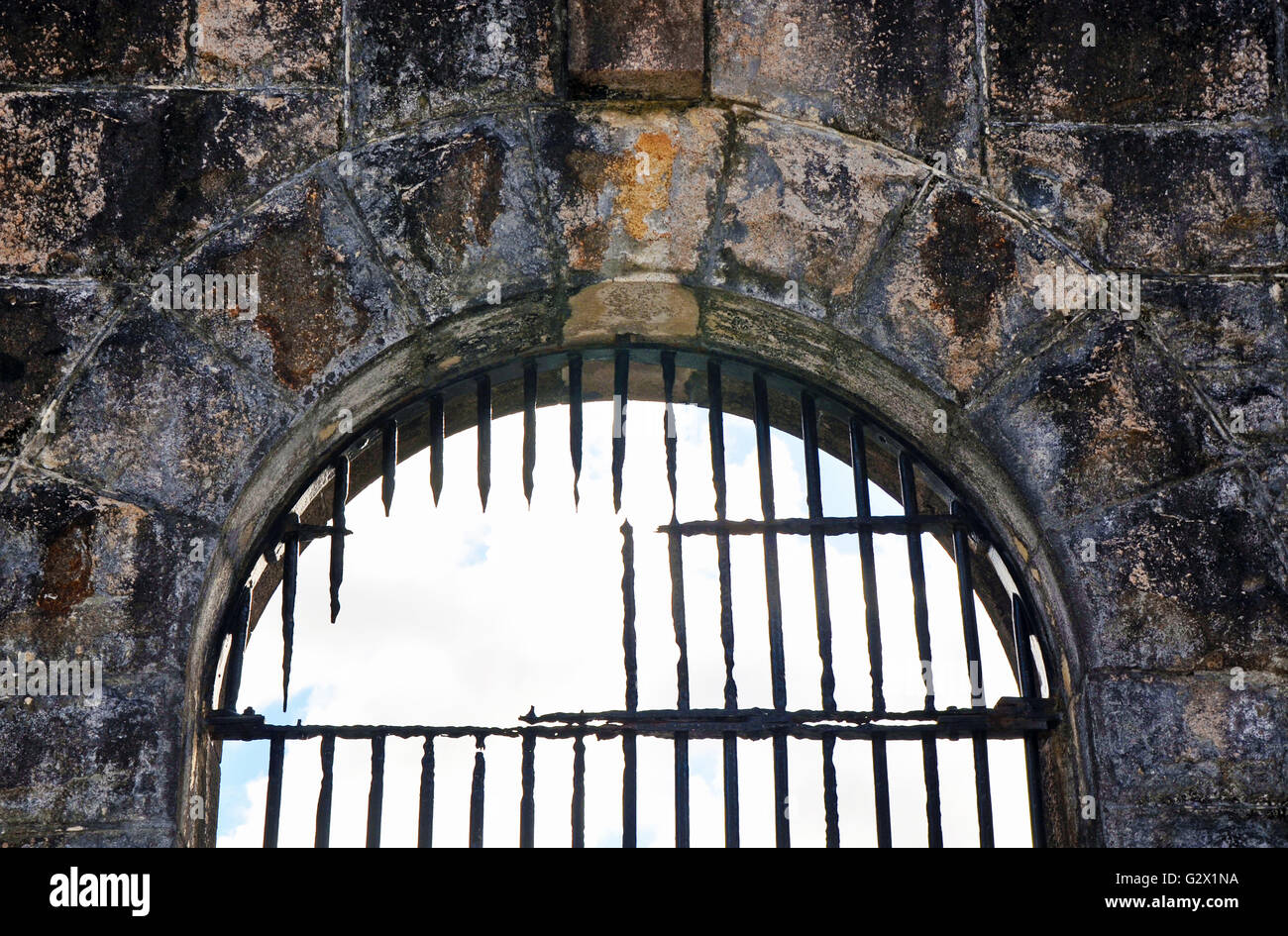 Rusty cassé des barres de fer sur l'ancienne prison (prison) fenêtre en arc- preuve d'une évasion ou jailbreak Banque D'Images