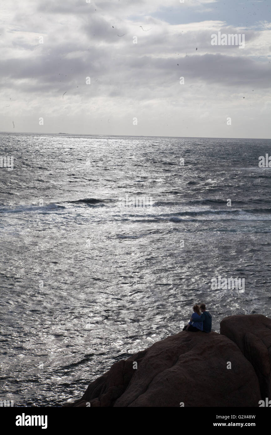 Deux personnes s'asseoir sur le rivage rocailleux, regardant la mer au large du Cap Leeuwin, Australie occidentale Banque D'Images