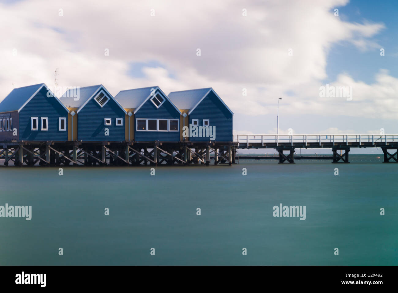 Une longue exposition, toujours de l'eau de mer et quatre petits bâtiments bleu sur Busselton Jetty, la plus longue jetée en bois. Banque D'Images