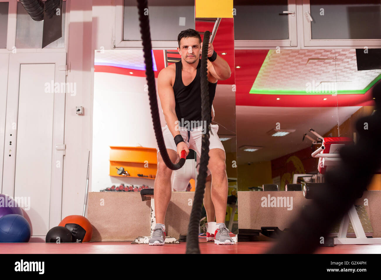Jeune homme travaillant sur des cordes de combat dans une salle de sport Banque D'Images