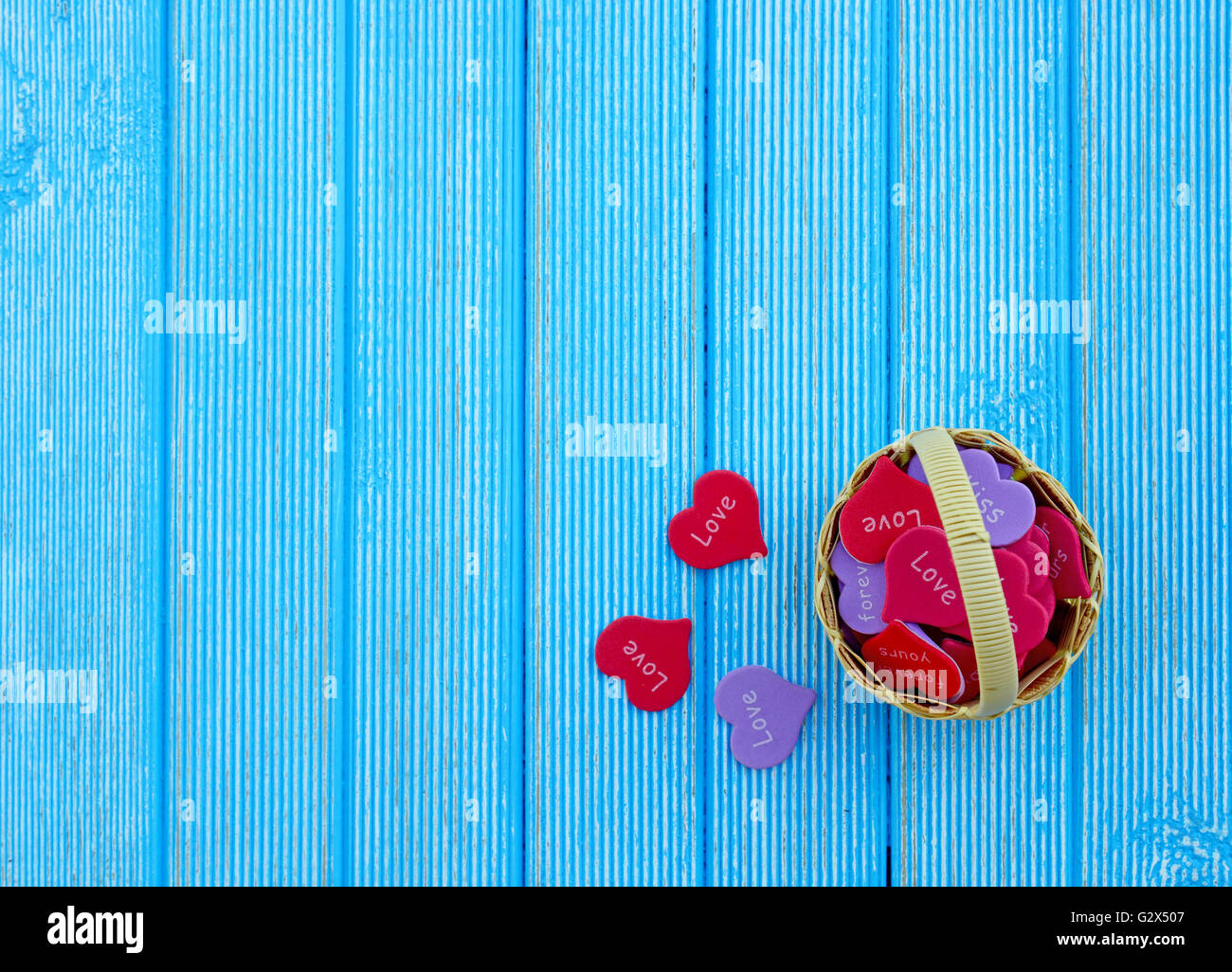 Fond d'amour. Panier plein de coeurs sur un fond de bois bleu Banque D'Images