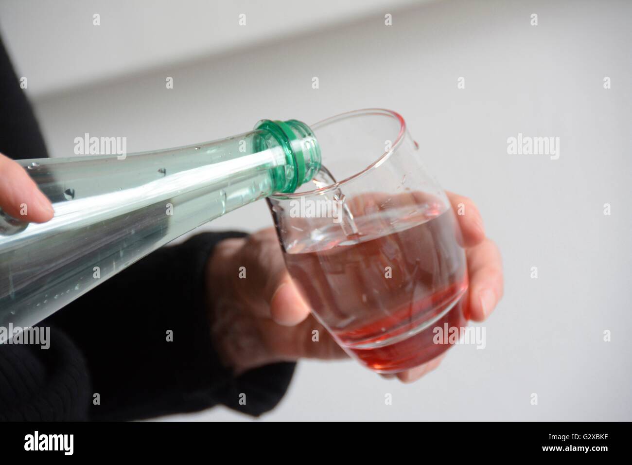 On verse de l'eau d'une bouteille dans un verre, France Banque D'Images