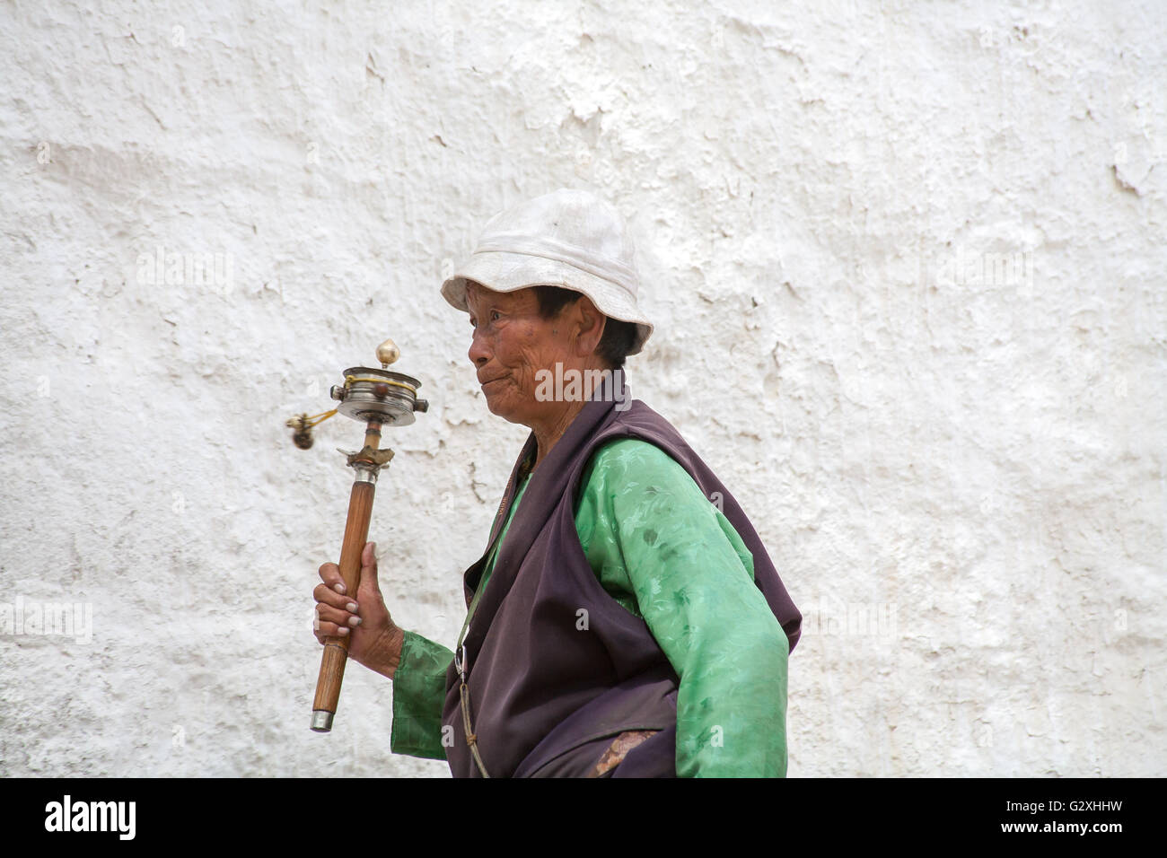 Pèlerin marchant à l'extérieur du monastère de Pabongka avec roue de prière, Tibet, Chine. Banque D'Images