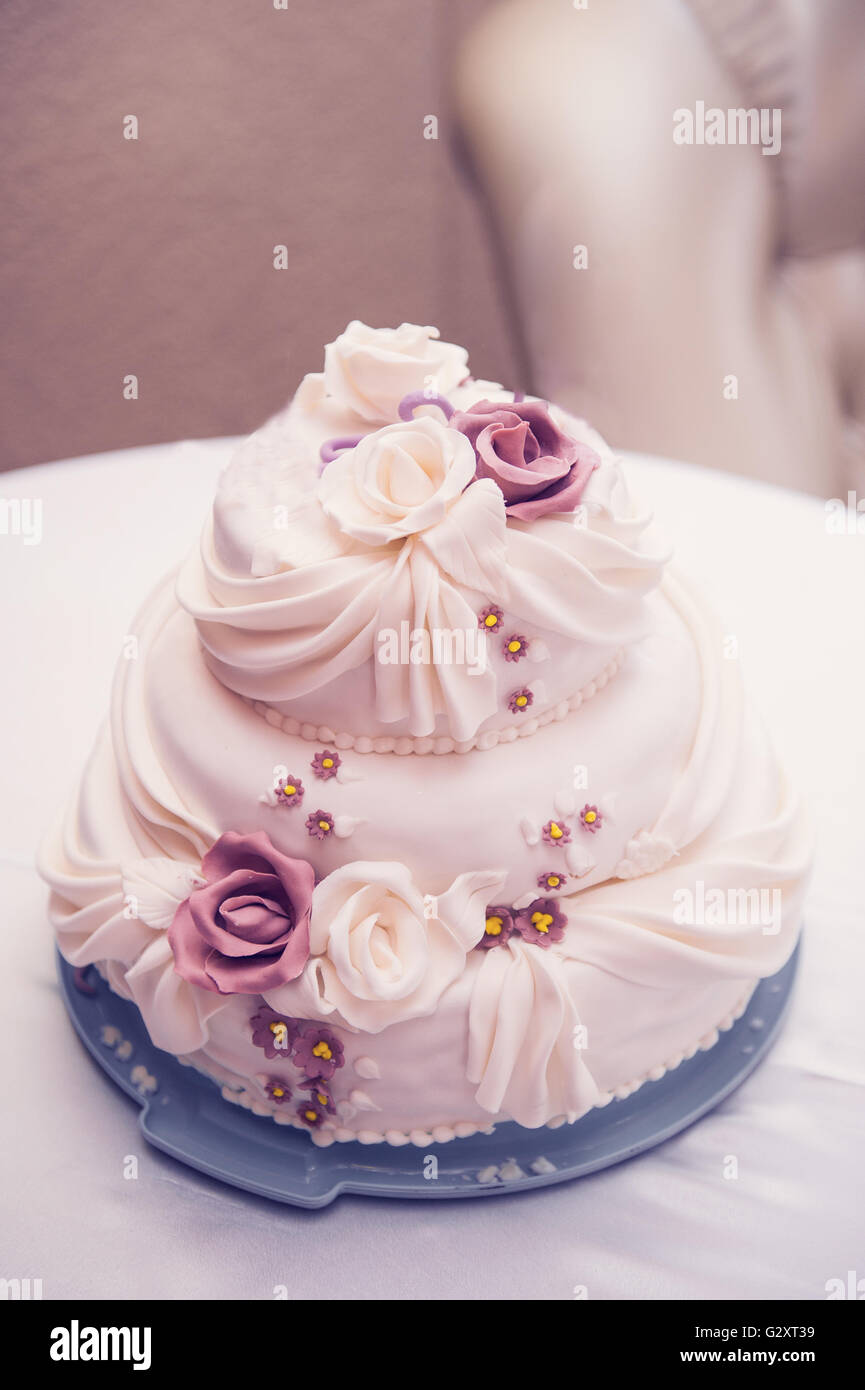 Trois niveaux, beau gâteau de mariage avec des roses sur la table Banque D'Images