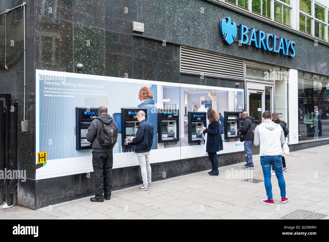 Extérieur de la Barclays Bank avec une ligne de personnes à l'aide de distributeurs automatiques sur la carbonisation Cross Road, London, England, UK Banque D'Images