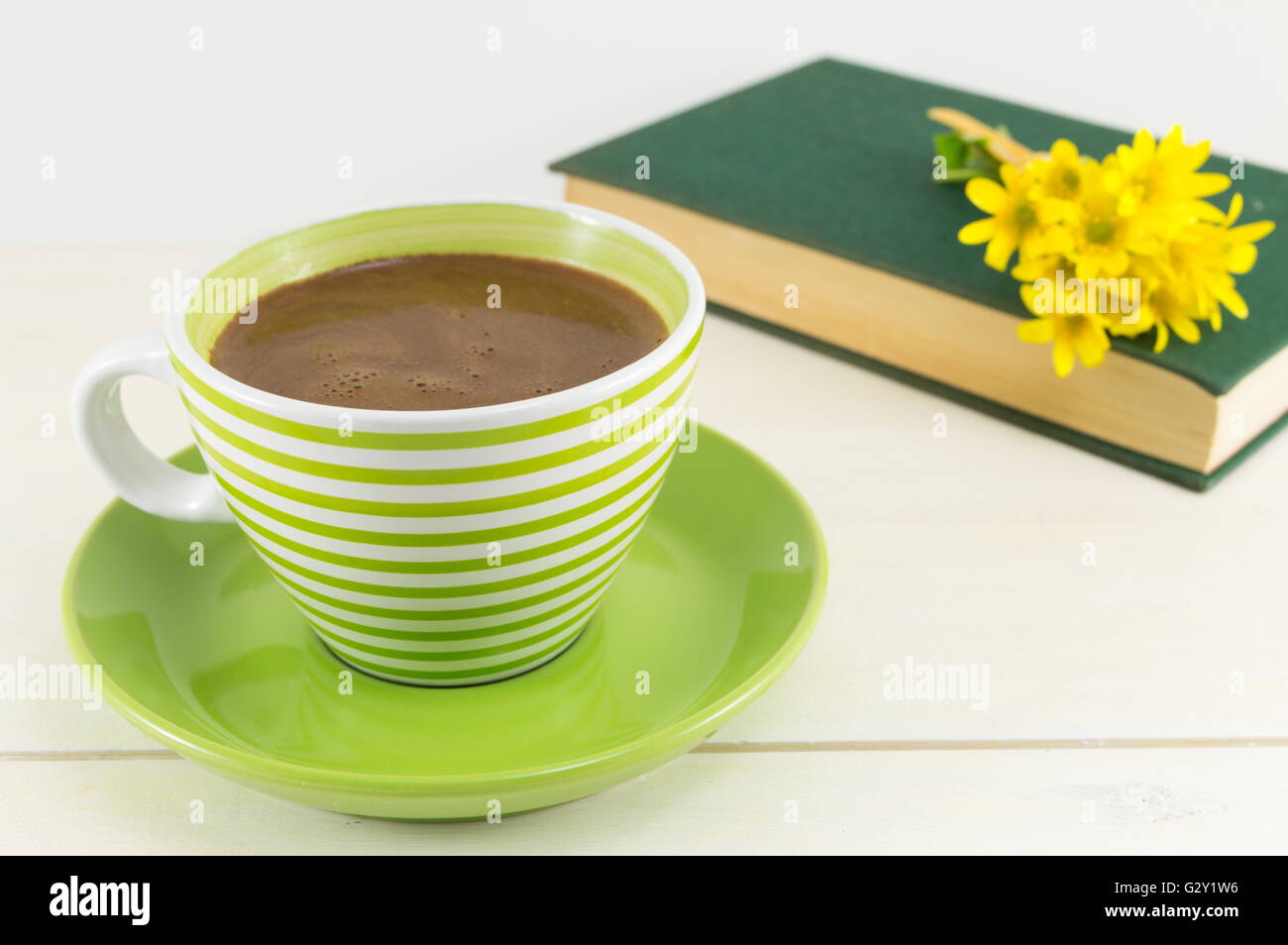 Tasse de café avec des fleurs fraîches et un livre sur une table Banque D'Images