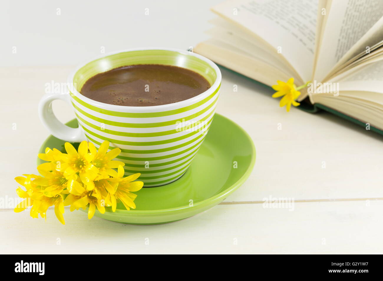 Tasse de café avec des fleurs fraîches et un livre sur une table Banque D'Images