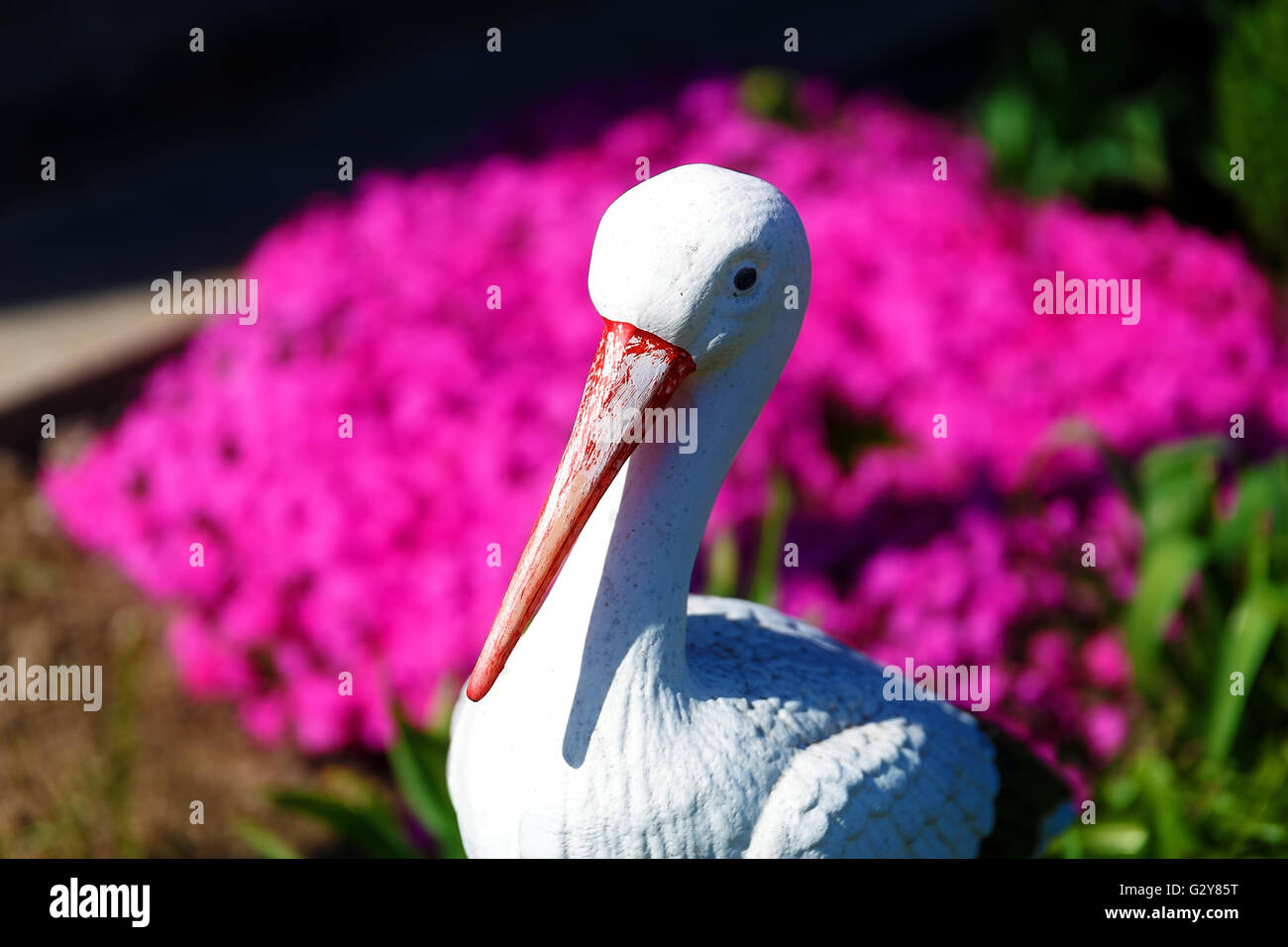 Stork sculpture dans jardin avec fleur pourpre. Banque D'Images