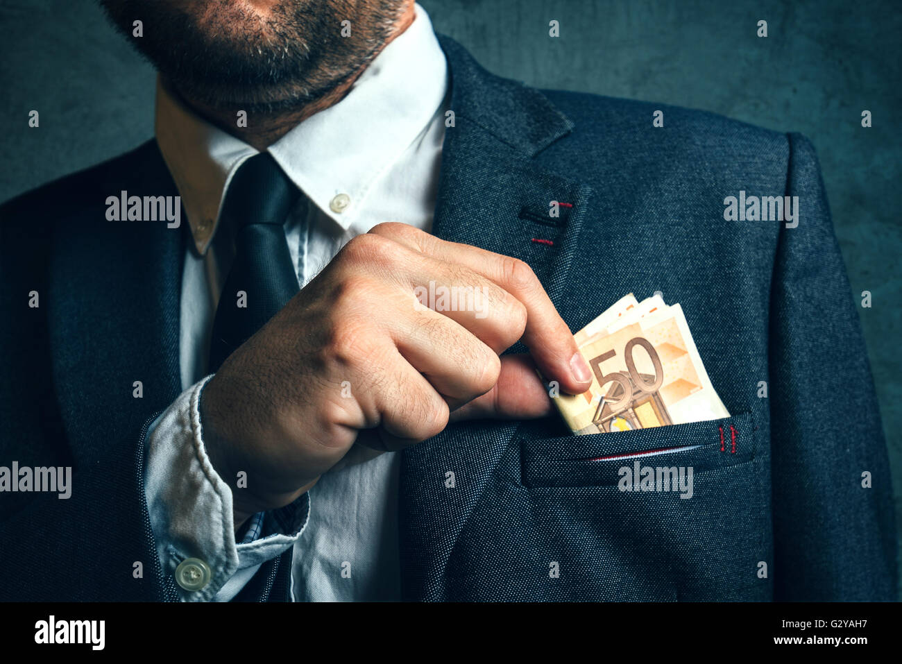 Businessman mettant de l'argent de l'argent dans sa poche, l'homme d'affaires élégant avec des billets en euros Banque D'Images