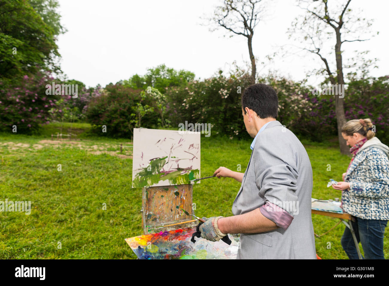 Middle-aged male et femelle peintres debout devant leur croquis photos peinture à l'huile et acrylique peinture durant une classe d'art dans un parc. Banque D'Images
