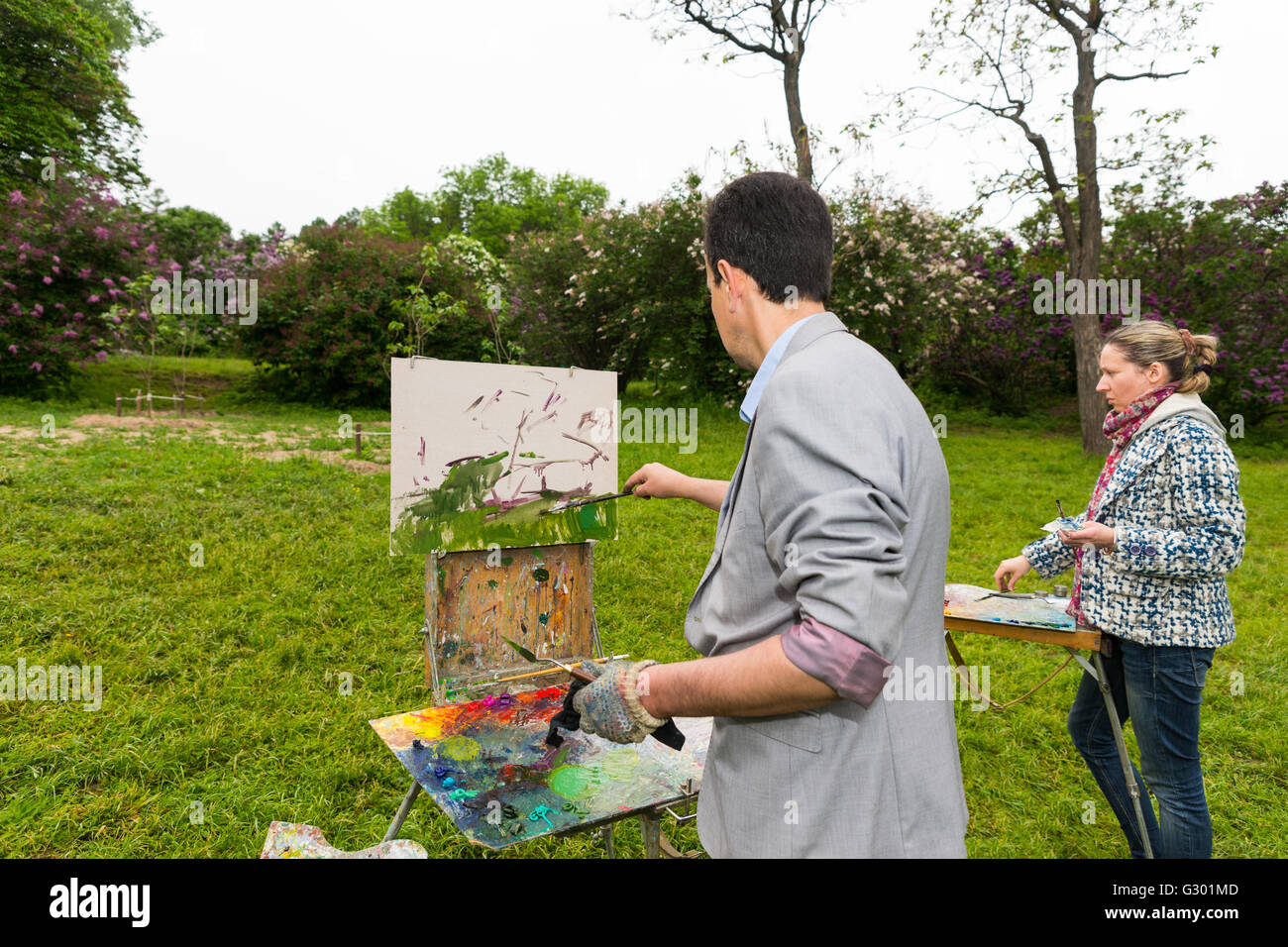 Mode d'âge moyen des peintres, hommes et femmes se tenant devant leurs carnets photos peinture à l'huile et acrylique peinture durant une classe d'art dans un parc. Banque D'Images