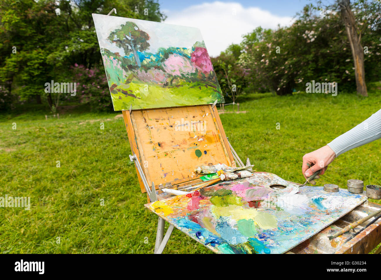 La main du peintre des femmes travaillant avec paletteknife et mélangeant les couleurs sur la palette multicolore de mélange des peintures à l'extérieur Banque D'Images
