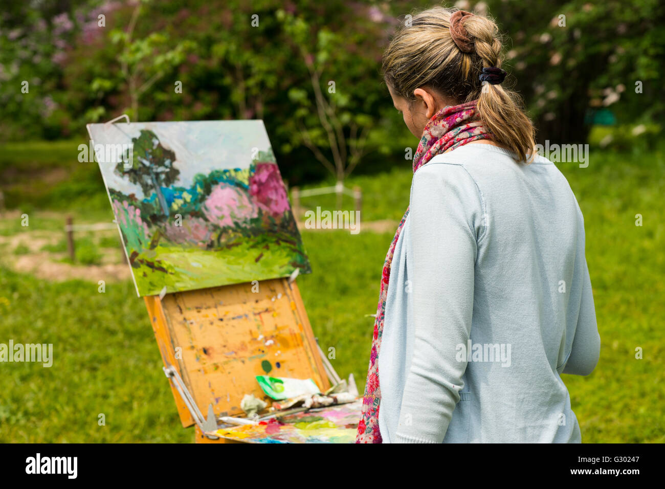 Vue arrière d'un artiste féminine travaillant sur un tréteau et peinture de  chevalet avec des huiles et acryliques à l'extérieur la peinture d'une  scène de jardin avec fleurs Photo Stock - Alamy