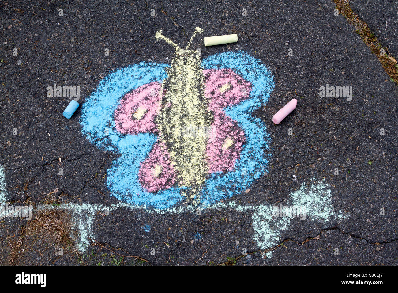 L'enfant dessin à la craie d'un papillon sur une allée Banque D'Images