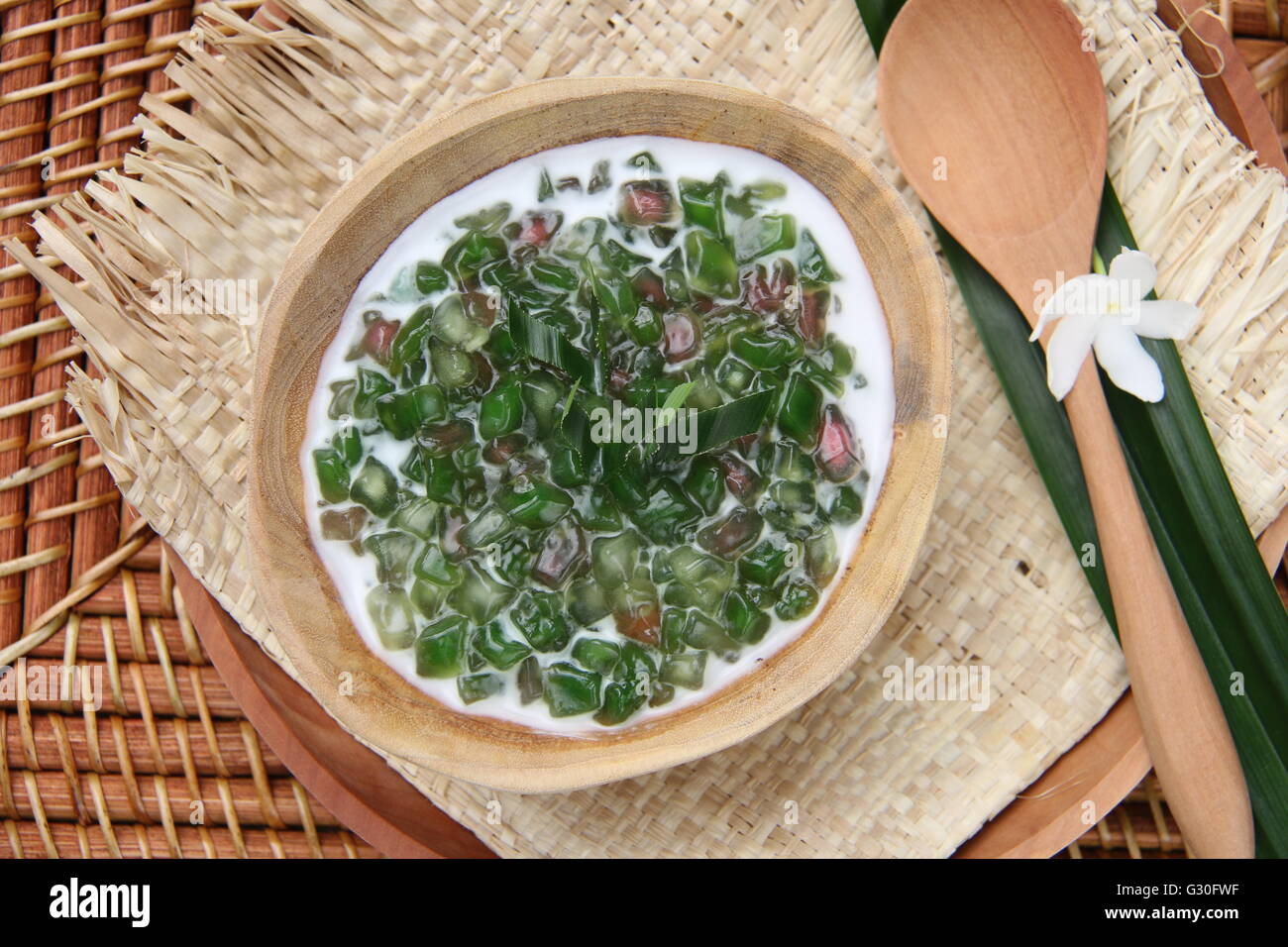 Porridge doux de vert et rose cubes de tapioca au lait de coco, sur un bol en bois fabriqué à partir de grains entiers de morceau de bois de teck. Banque D'Images