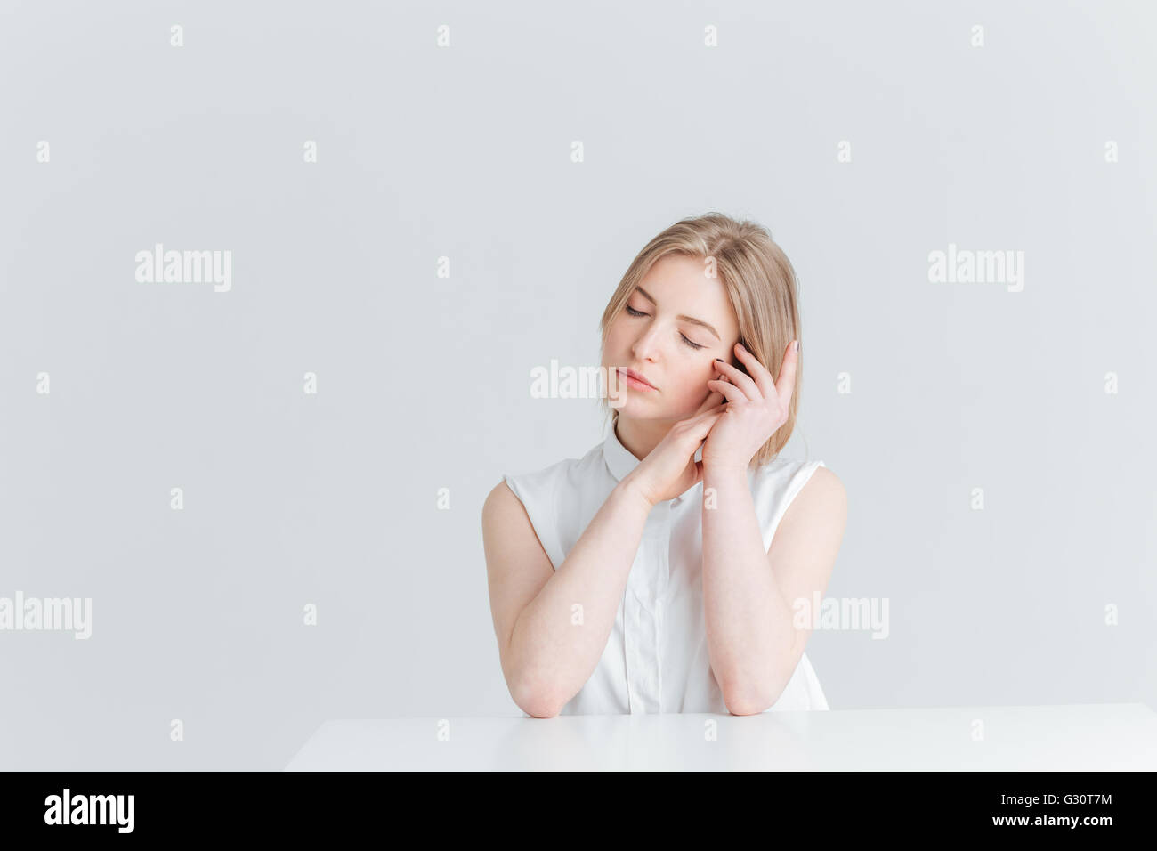 Portrait de beauté d'une jeune femme détendue assis à la table isolé sur fond blanc Banque D'Images