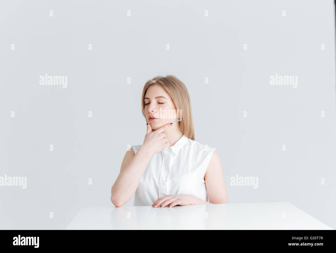 Portrait de beauté d'une jeune femme aux yeux clos à la table isolé sur fond blanc Banque D'Images