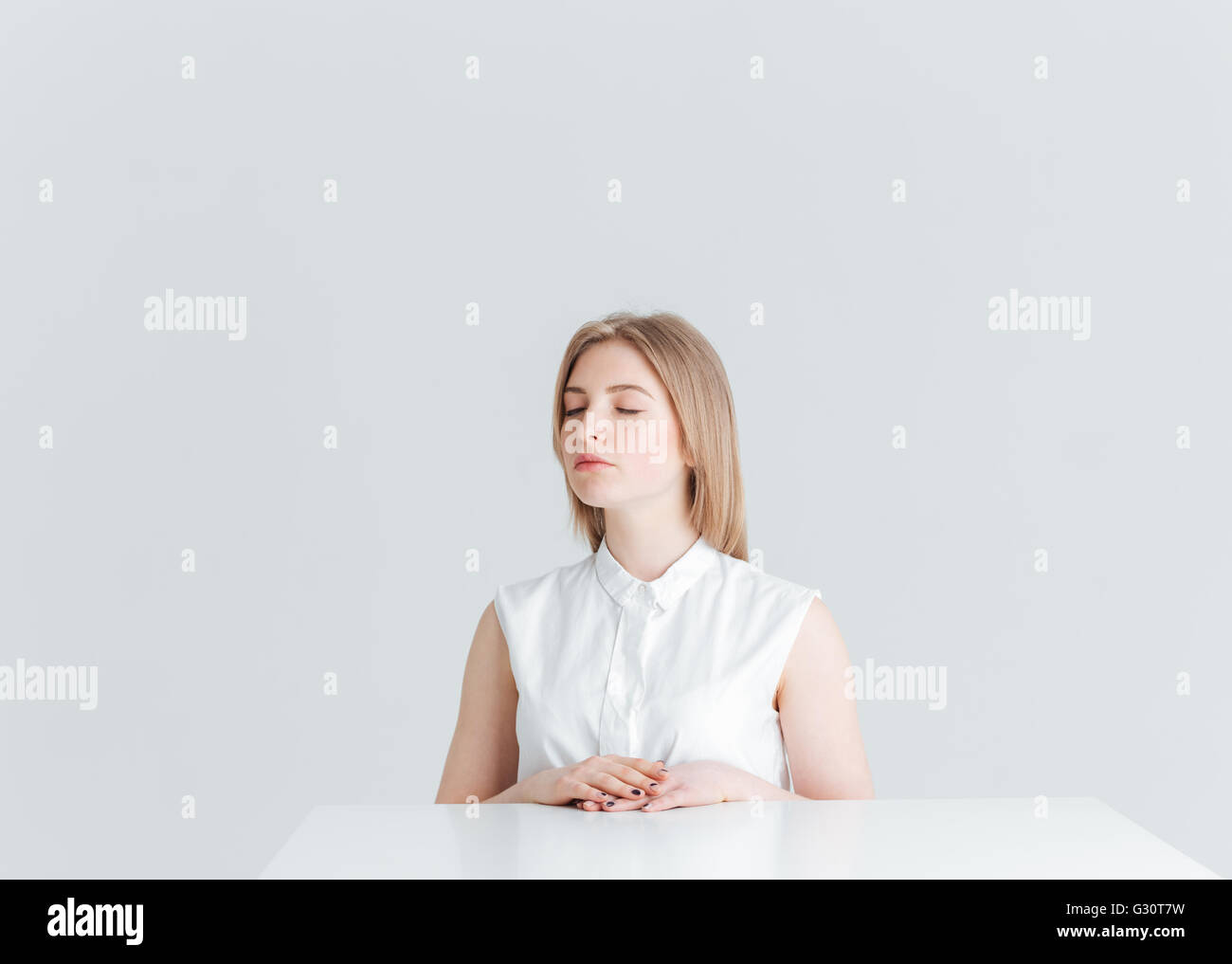 Jeune femme détendue avec les yeux fermés à la table isolé sur fond blanc Banque D'Images