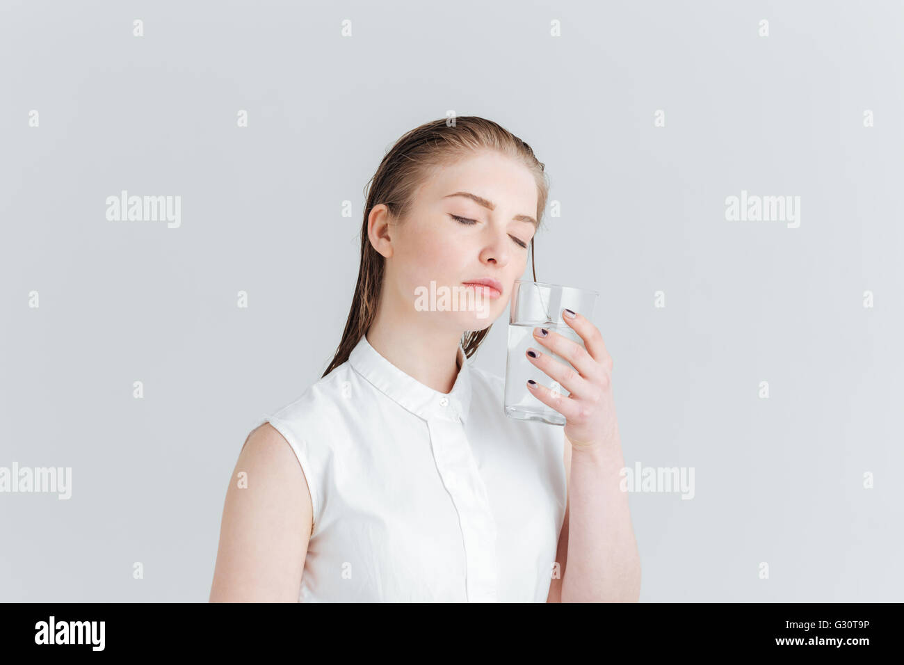 Portrait de femme beauté détendue avec la peau douce holding glass of water isolé sur fond blanc Banque D'Images