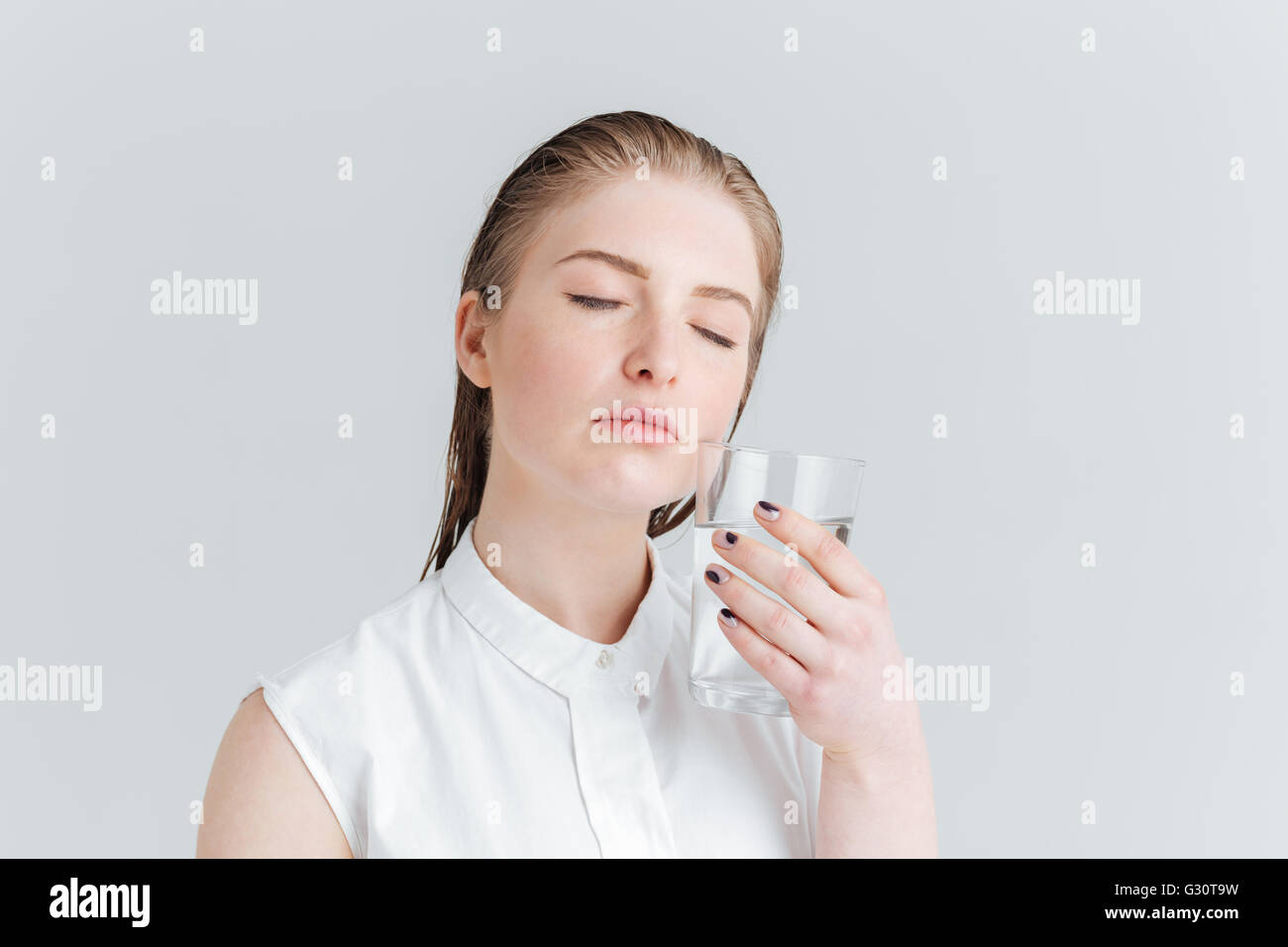 Portrait de beauté d'une jeune femme aux yeux clos holding glass of water isolé sur fond blanc Banque D'Images