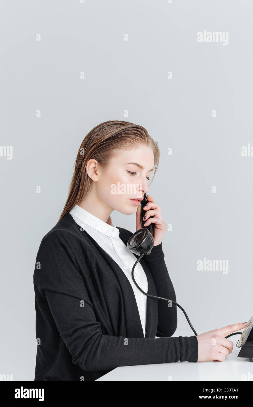 Young businesswoman talkign sur retro phone isolé sur fond blanc Banque D'Images