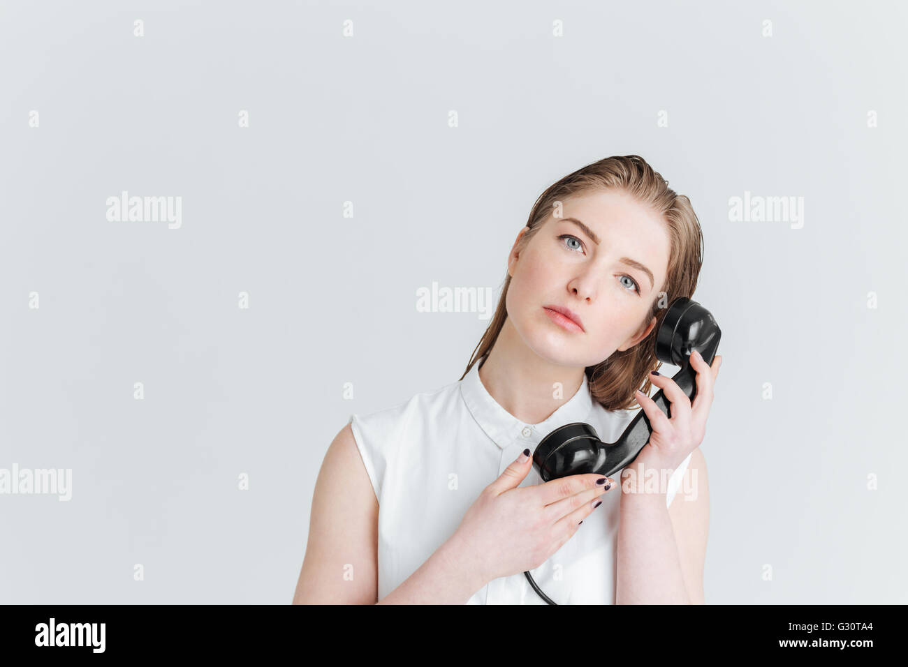 Jeune femme avec de sking holding retro phone tube et looking at camera isolé sur fond blanc Banque D'Images