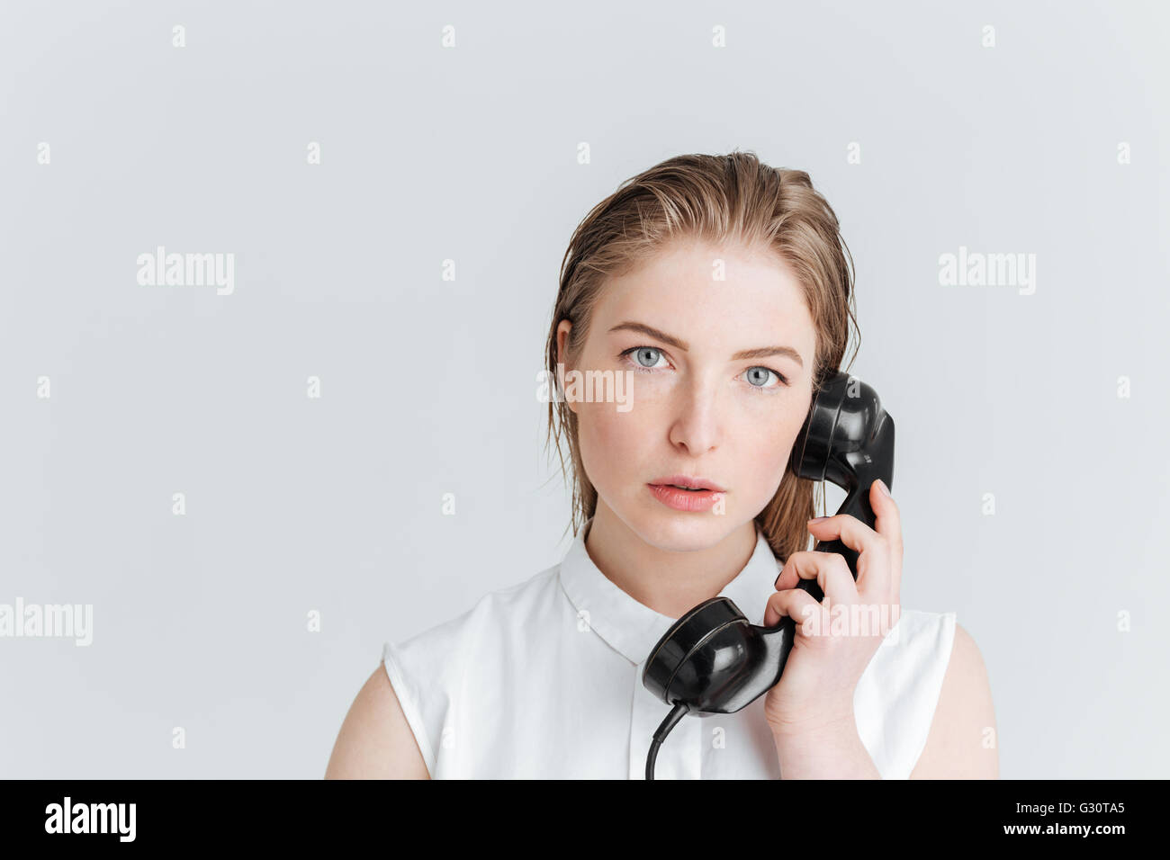Jeune femme parlant au tube rétro isolé sur fond blanc Banque D'Images