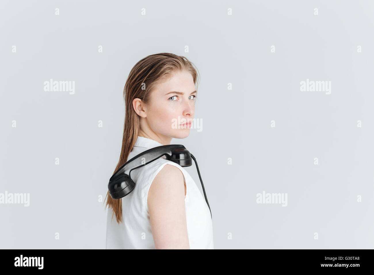 Jeune femme debout avec retro phone tube sur l'épaule et à la caméra à isolé sur fond blanc Banque D'Images