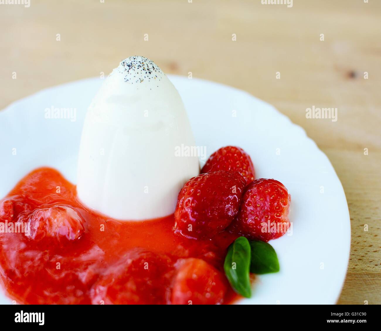 Panna Cotta aux fraises, fraises et de feuilles de basilic sauce sur plaque blanche. Banque D'Images