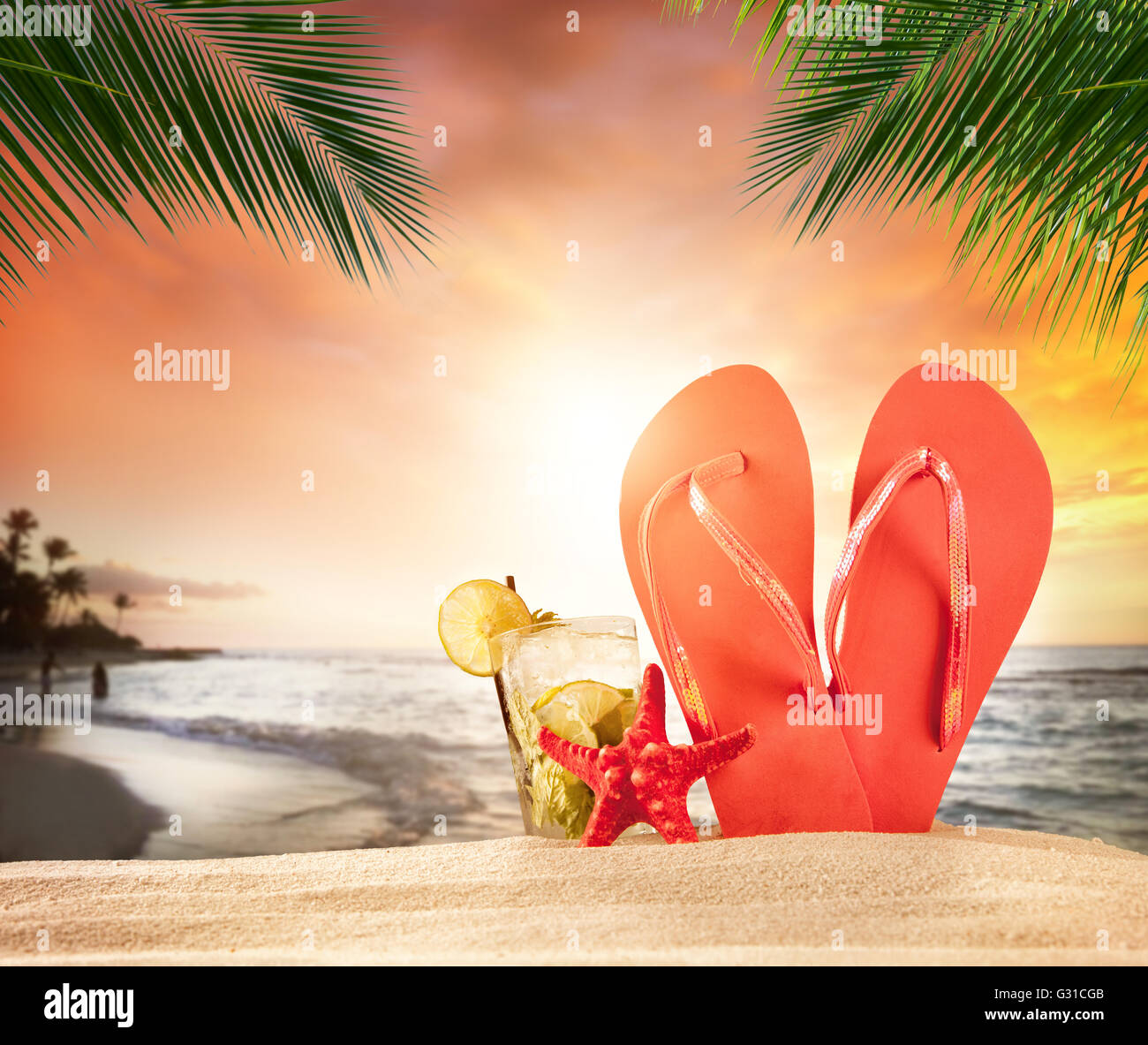 Plage tropicale avec un verre et des accessoires dans le magnifique coucher de soleil avec des feuilles de palmier sur le premier plan. Copyspace pour le texte Banque D'Images