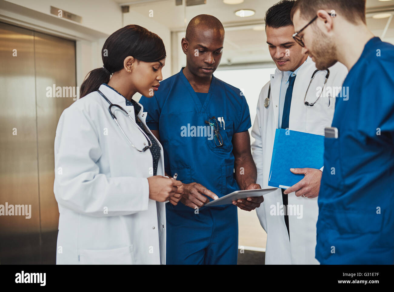 De l'équipe multiraciale doctors discussing un patient debout regroupés dans le foyer à la tablette à un ordinateur, vue en gros Banque D'Images
