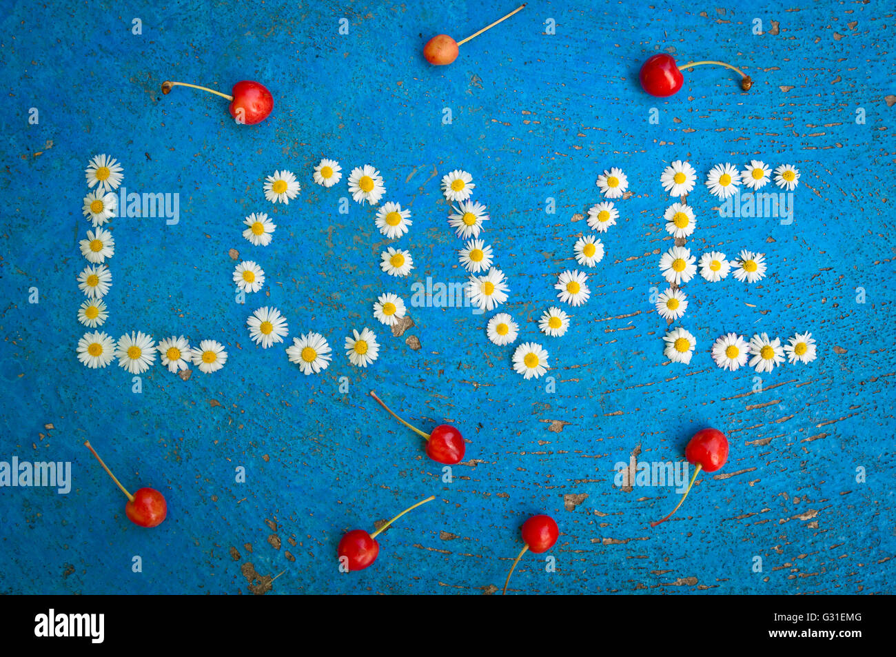 Le mot amour written de daisy fleurs sur fond bleu texturé, vue du dessus Banque D'Images