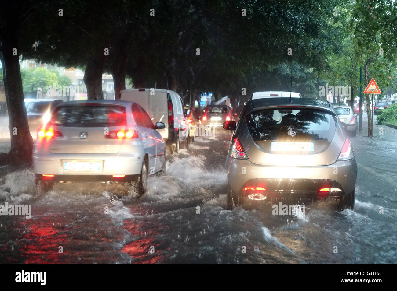 Aci Trezza, Italie, les voitures roulent sur une rue inondée par l'eau de pluie Banque D'Images