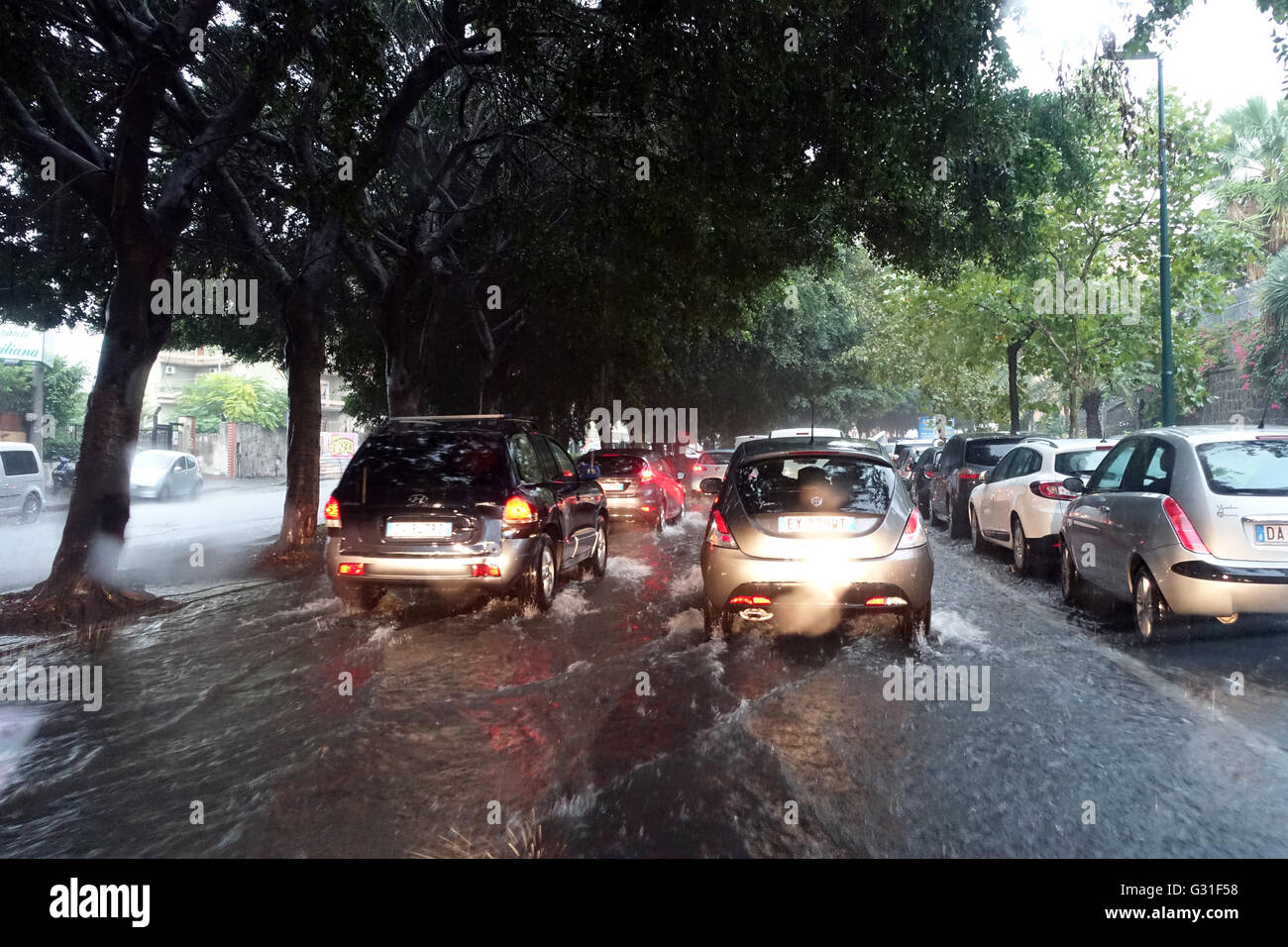 Aci Trezza, Italie, les voitures roulent sur une rue inondée par l'eau de pluie Banque D'Images