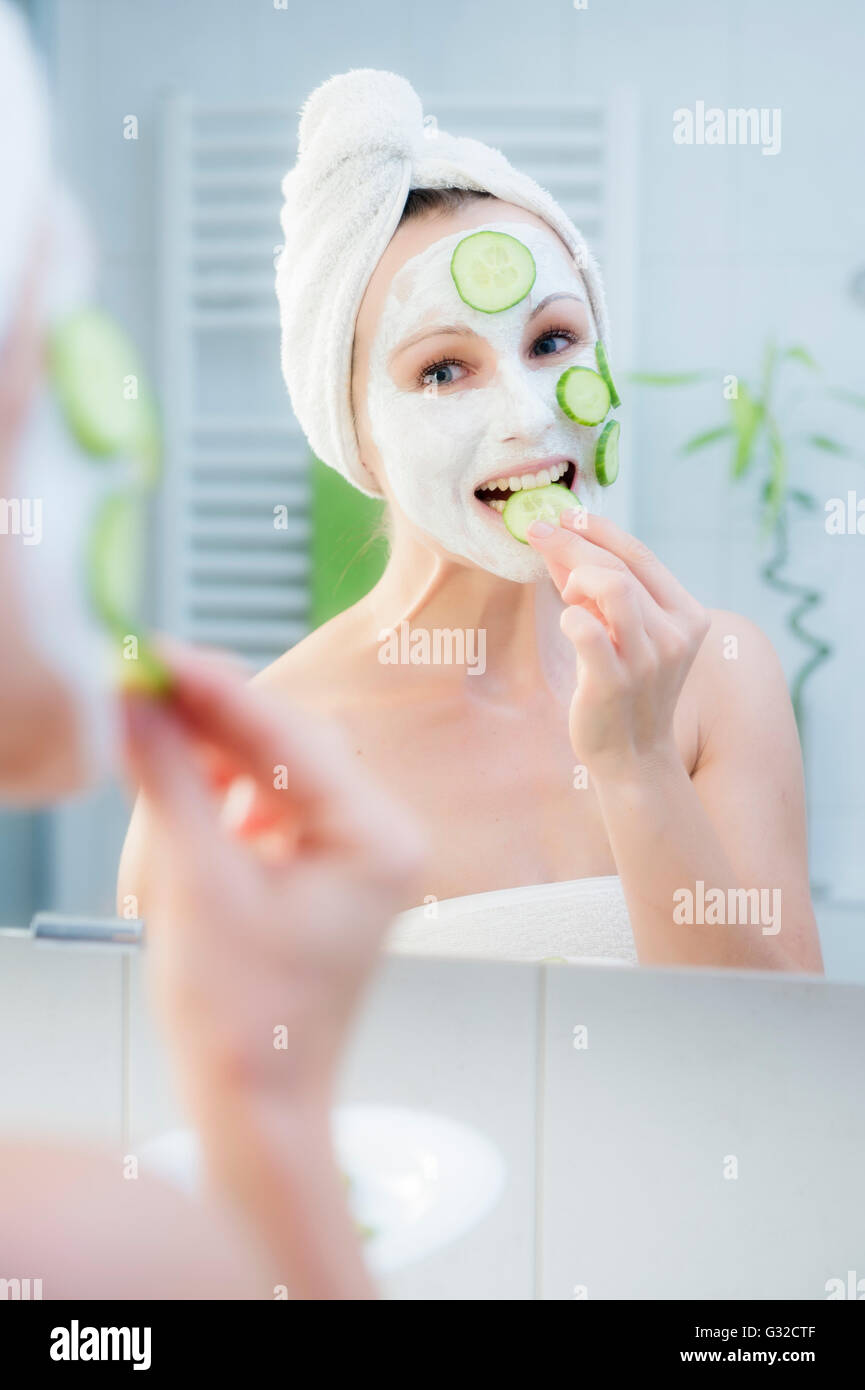 Femme, 30 +, dans la salle de bains l'application de tranches de concombre pour un masque facial Banque D'Images