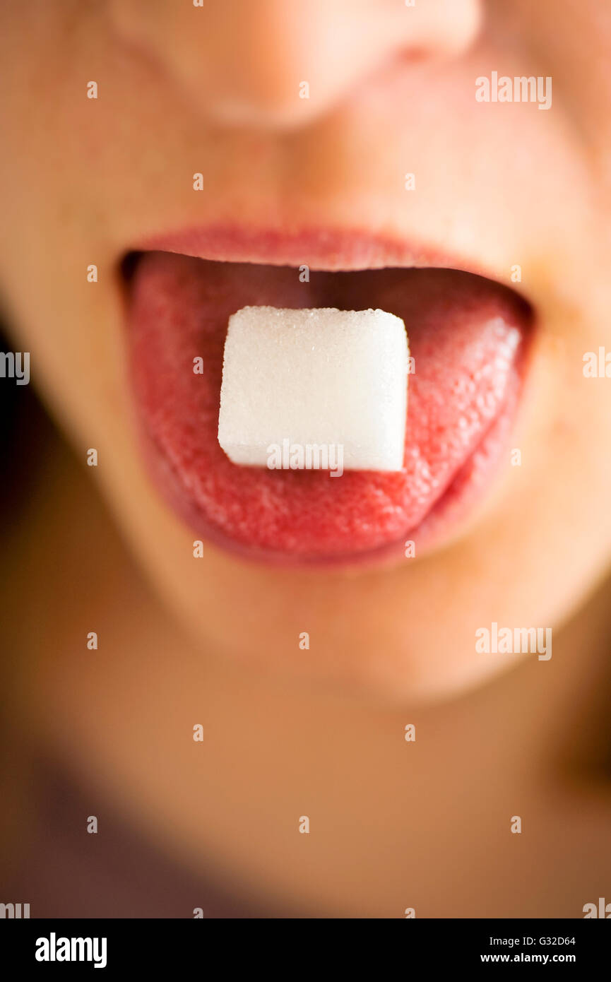 Femme avec cube de sucre sur sa langue Banque D'Images