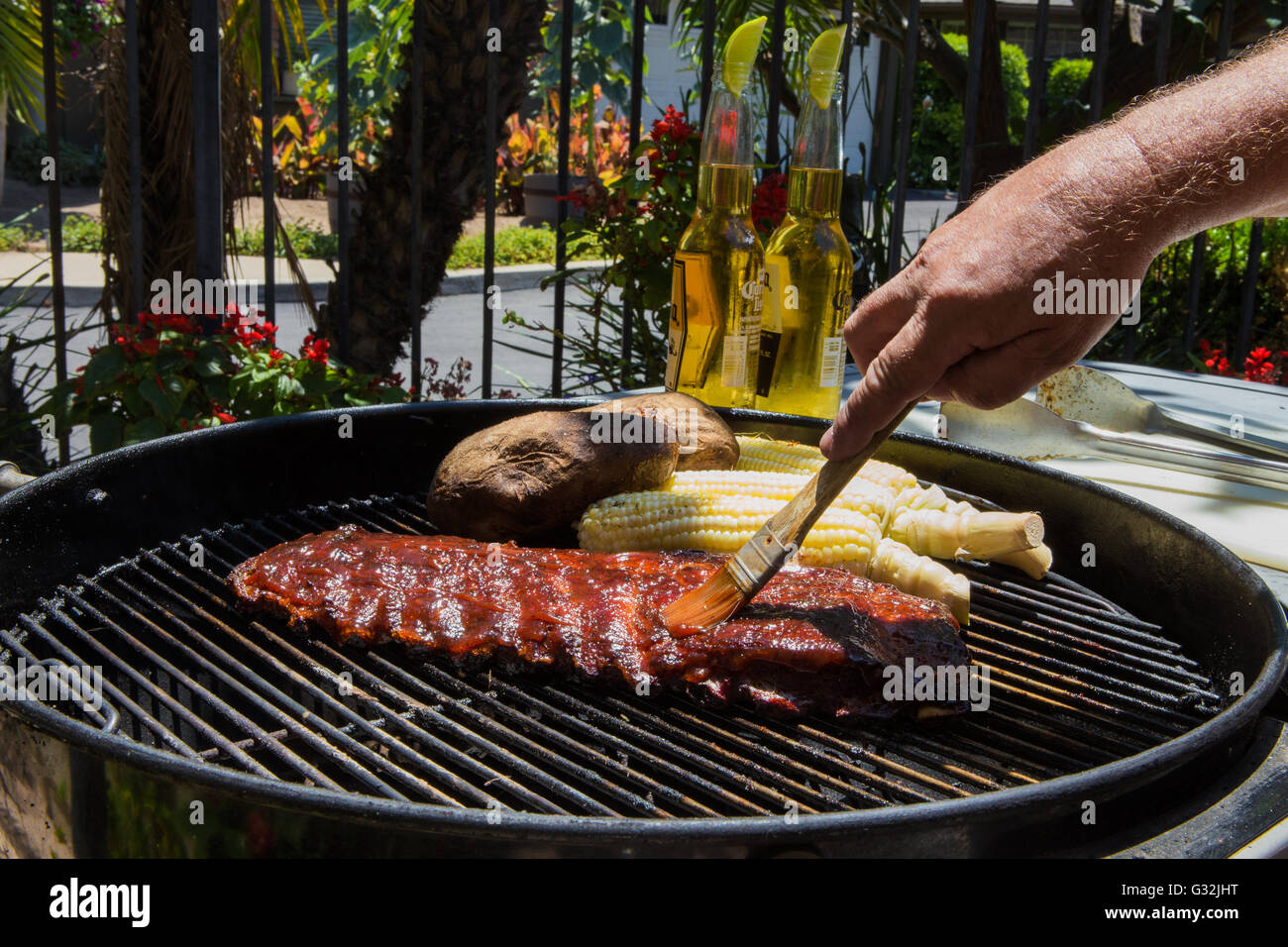 Bébé barbecue côtes de porc en retour, du maïs et des pommes de terre  cuites à l'extérieur, sur un gril de charbon de bois dans un jardin Photo  Stock - Alamy