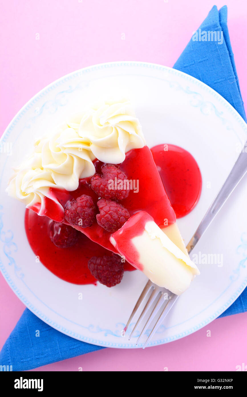 Tranche de gâteau au chocolat blanc avec coulis de framboise et framboises fraîches. Banque D'Images