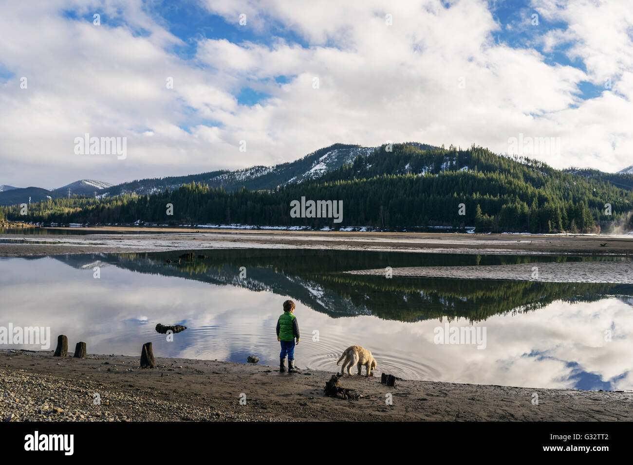 Garçon debout près du lac avec chiot golden retriever dog Banque D'Images