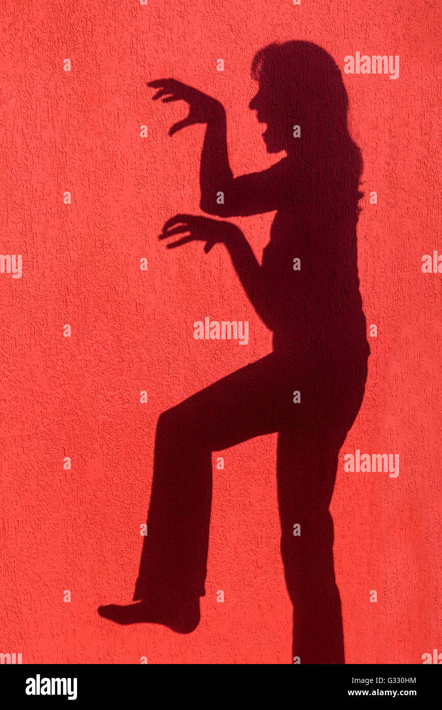 Ombre silhouette de femme en colère on red wall Banque D'Images